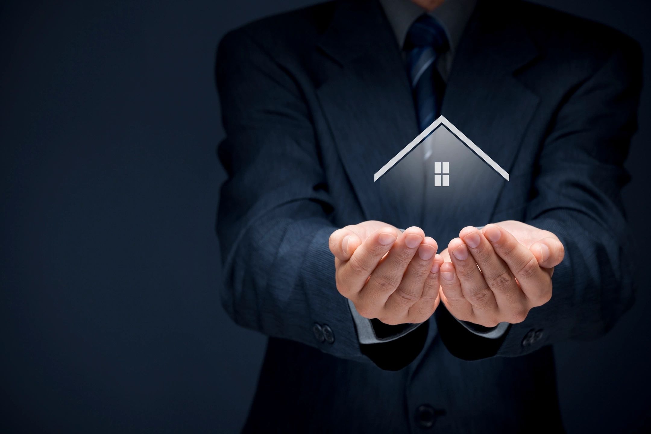 Businessman holding house icon representing trust in real estate